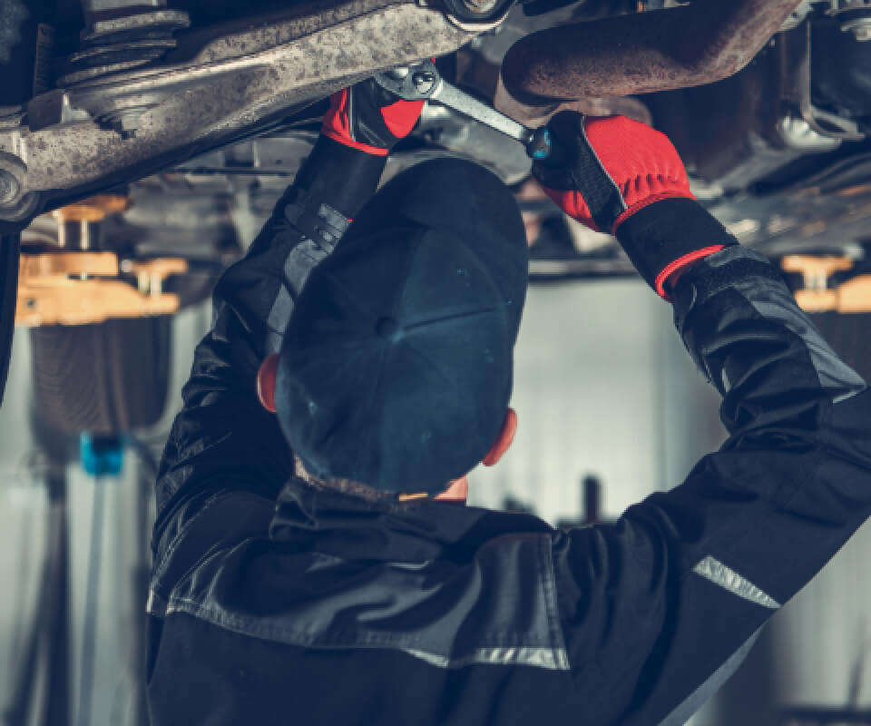 リフターで高く上げられた車の下回りの点検作業をしている様子