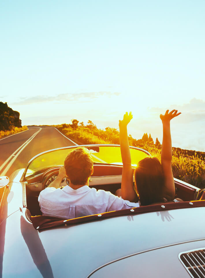 オープンカーに乗っているカップル道路を走行している様子