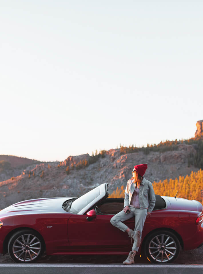 見晴らしのいい丘の上に車を停めて景色を見ている女性