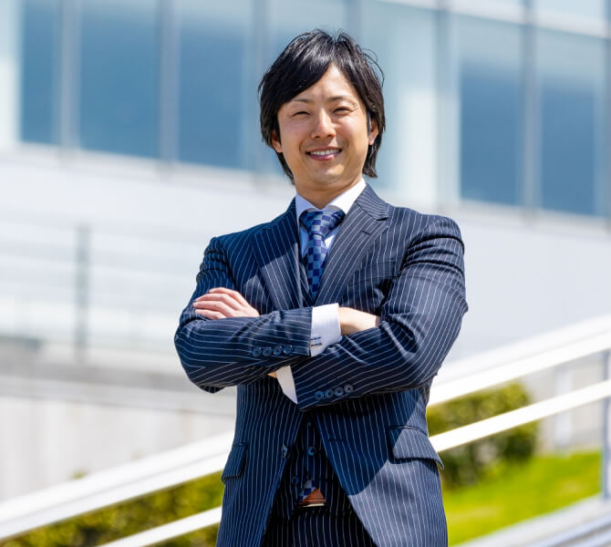 笑顔で腕組みのポーズで正面を見ている代表取締役の田中太郎氏