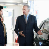 カーディーラーの担当者から車の説明を受けている様子